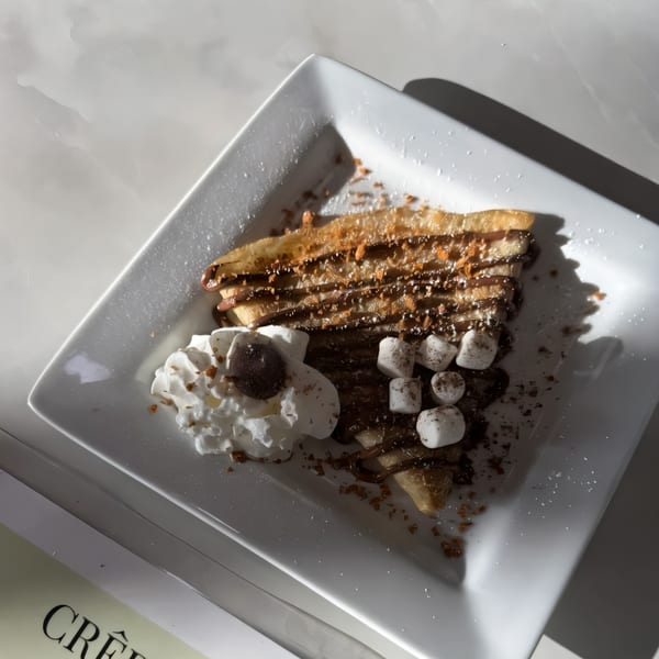A chocolate crepe from The Crepe Club, topped with whipped cream, marshmallows, and chocolate drizzle.